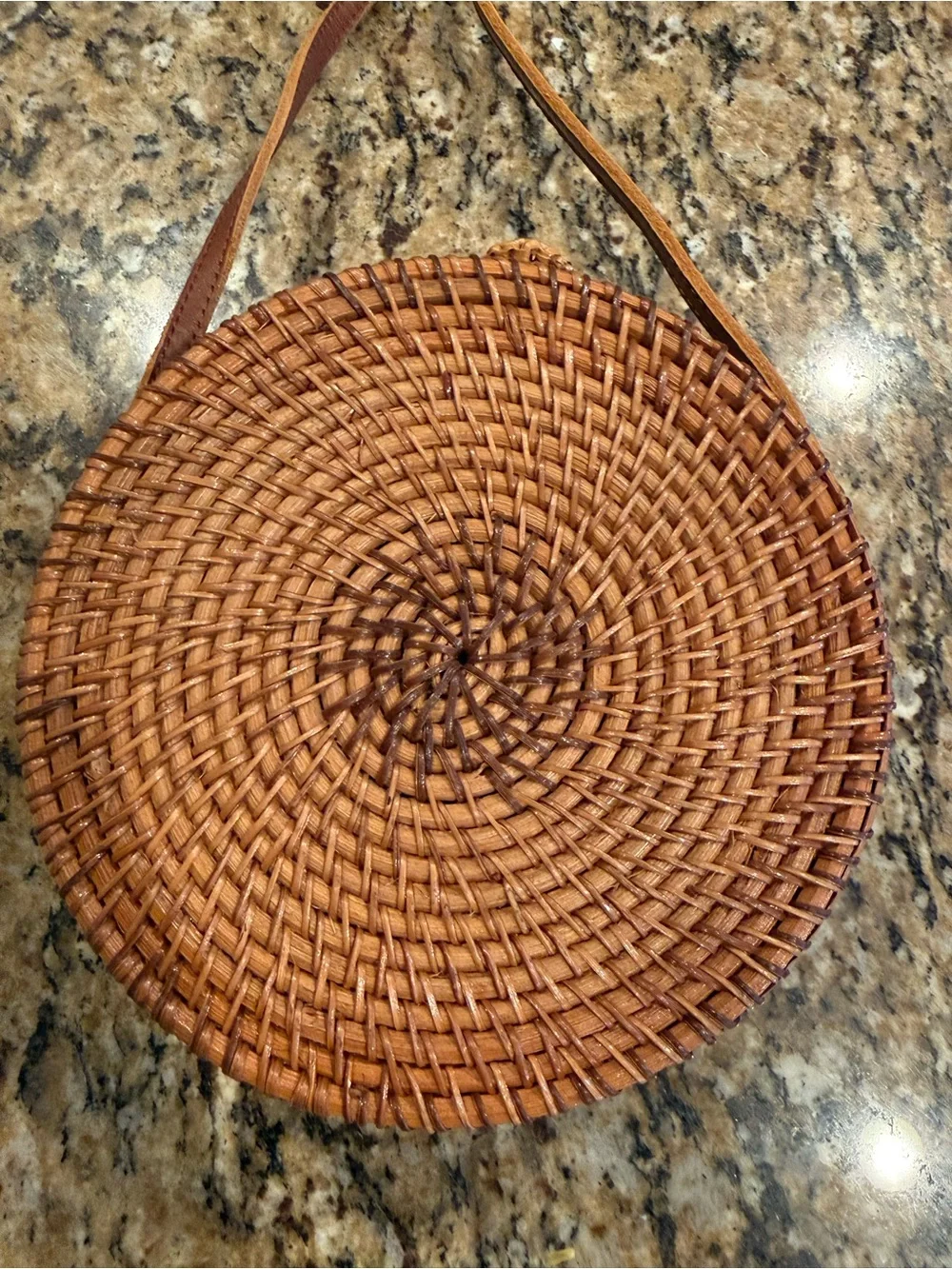 Tan, round, handwoven rattan crossbody bag